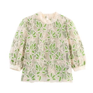Détail de la broderie florale sur haut en dentelle crème avec feuilles vertes et mesh