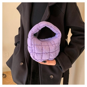 Close-up of a purple quilted puffer cloud bag worn by a model in an indoor setting