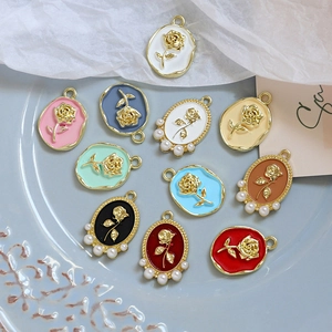 Vintage rose pendant in alloy with pearls, displayed in multiple colors on a blue plate