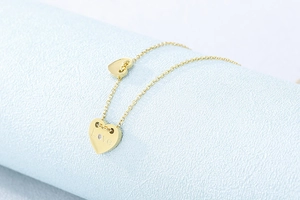 Makroaufnahme des goldenen Herzanhängers mit Love-Gravur und kleinem Diamanten