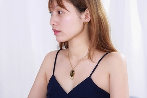 Gros plan d'un collier cœur doré à plusieurs rangs et de boucles d'oreilles sur modèle