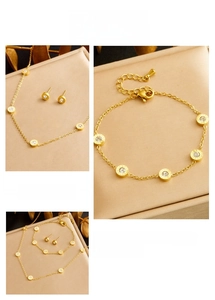 Macro detail of gold plated necklace set featuring roman numeral round crystal charms