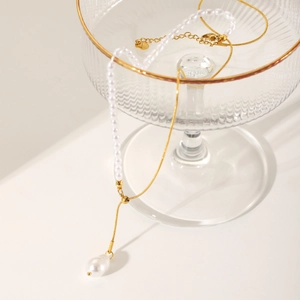 Detailed close-up of gold snake chain with white pearls on a glass rim decoration