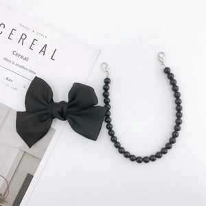 Handmade black fabric bow with beaded lanyard and silver lobster clasp on a white desk
