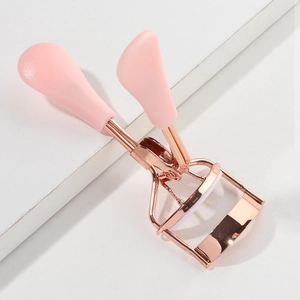 Close-up of rose gold eyelash curler with pink handles and silicone pad on white podium