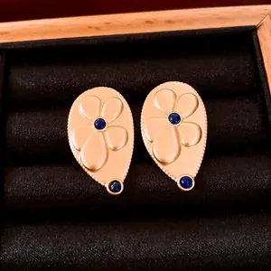 Vintage gold teardrop earrings with embossed flowers and blue stones in a jewelry box