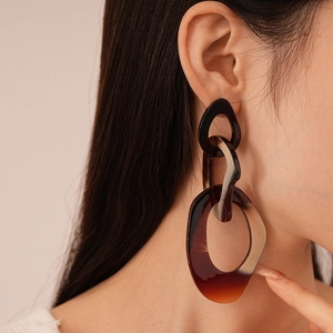 Close-up of chunky tortoiseshell resin chain earrings worn on a model for a chic look
