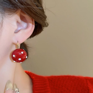 Close-up of a model wearing a red polka dot pearl ball earring with gold plating