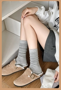 Close-up of grey ribbed combed cotton socks paired with khaki faux shearling slippers