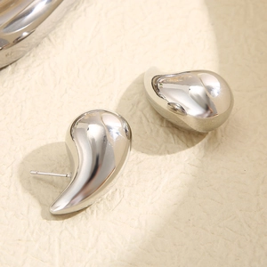 Polished silver teardrop earrings with a mirror finish on beige textured background