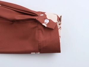 Détail du poignet à volants rouge-brun avec doublure camouflage et petit bouton blanc