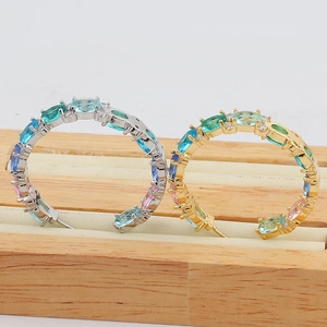 Macro detail of gold and silver hoop earrings with multicolored oval zirconia stones