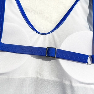 Detail of royal blue swimsuit strap with silver metal adjuster on white textured fabric