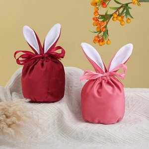Deep red and pink velvet bunny ear gift bags with satin ribbons on white knit fabric