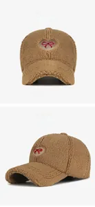 Detail of brown faux fur baseball cap with heart and bow embroidery for winter