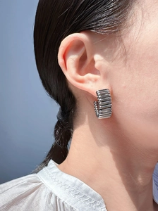 Close-up of stylish C-shaped silver earrings with wavy texture on female model