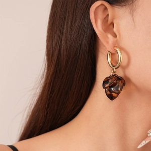 Detail of amber heart earrings with tortoise pattern and gold hoop on model