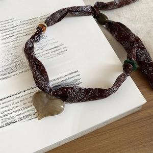 Close-up of heart pendant necklace with paisley fabric and amber resin texture