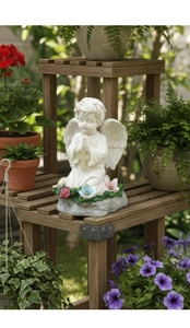 Detalle de estatua de ángel rezando en resina con cruz en soporte de madera de jardín