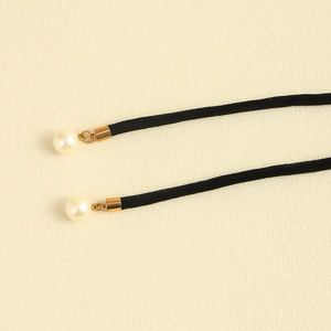Detail of black velvet waist cord with cream pearl charms and gold metal tips