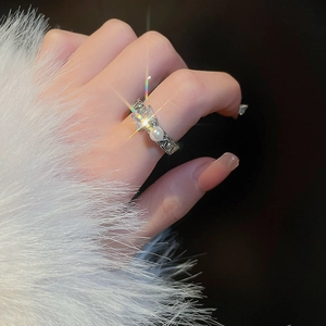 Macro shot of silver ring featuring a square cut zircon and round white pearl