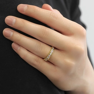 Close-up of a gold geometric ring with alternating pink and white crystals on finger