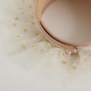 Detail of children straw sun hat with pink woven texture and gold polka dot lace trim