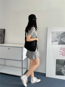 Borsa a tracolla in nylon stile dumpling indossata da una modella con un abito grigio