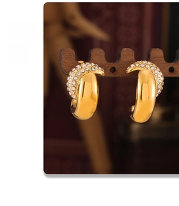 Detail of gold crescent earrings with inlaid rhinestones on a wooden stand