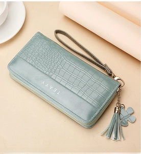 Detail view of light cyan crocodile pattern long wallet with flower tassel and wristlet