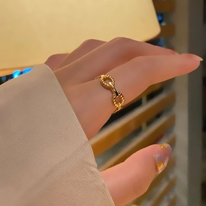 Detail of a gold stainless steel double ring with twisted rope texture worn by a model