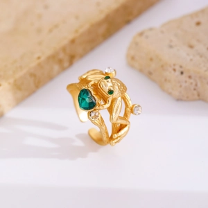 Detailed shot of a golden frog ring holding a green heart zircon on a stone pedestal