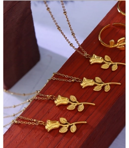 Detail of rose-shaped gold necklace and ring jewelry set on red wood texture