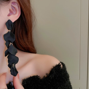 Detail of long black flower petal tassel earrings with gold rings on a model