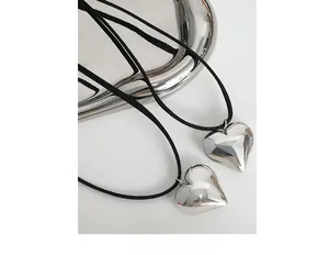 Detailed view of puffed heart pendants in polished silver on black cord necklaces
