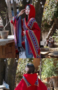 Détail d'un poncho rouge à capuche avec motifs ethniques et élégantes franges