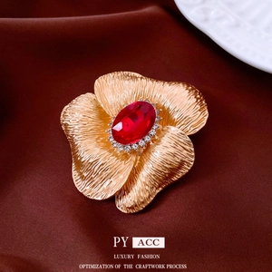 Vintage gold flower brooch with red gemstone and crystal halo on luxury velvet fabric