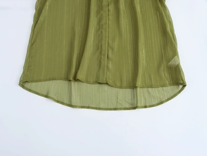 Close-up of olive green chiffon hem with subtle gold vertical stripes and curved edge