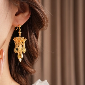 Close-up of gold-plated lotus leaf tassel earring worn by a model in natural light