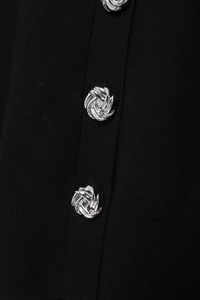 Detail of silver spiral metal button on black knitted cardigan texture