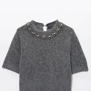 Top in maglia grigia a maniche corte con decorazioni in cristallo floreale sul collo