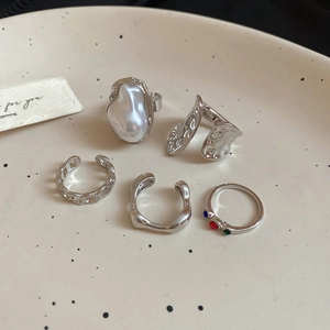 Close-up of diamond irregular flower rings and pearl earrings on a ceramic dish