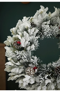 Close-up of frosted PE Christmas wreath with pine cones and red berries detail