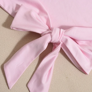 Close-up of pink crop top featuring textured fabric and delicate bow tie detail