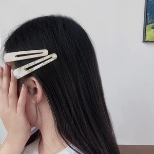 Acetate waterdrop duckbill hair clips with marble texture worn by a model in beige and green