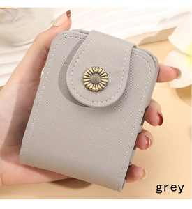 Detail of grey crossgrain leather makeup bag with a golden daisy metal clasp