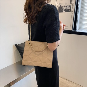 Detail of beige rectangular crossbody bag with geometric triangle stitching and gold chain