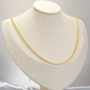 Detail shot of golden woven chain necklace displayed on a textured jewelry stand