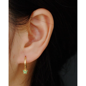 Close-up of gold S925 silver hoop earring with a green rhinestone butterfly pendant