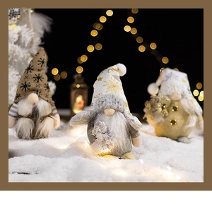 Close-up of three knitted Christmas gnomes with snowflake patterns and warm bokeh lights